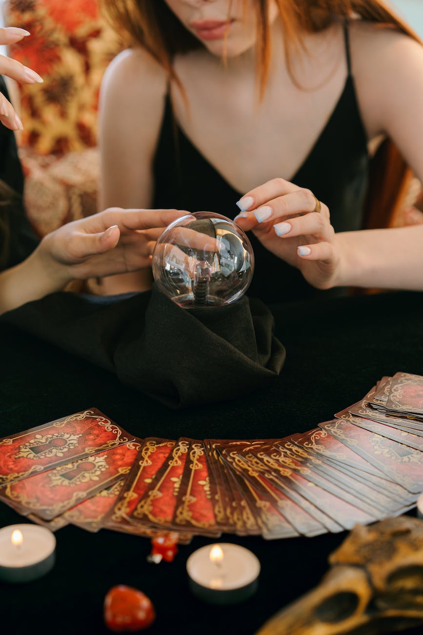 anonymous female soothsayers with crystal ball and tarot card during divination session
